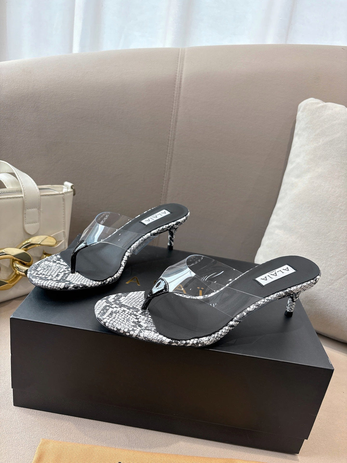 ALAIA HEELED THONG 25S 55 MM IN WHITE AND BLACK LAMBSKIN SNAKE-EMBOSSED WITH CLEAR STRAP